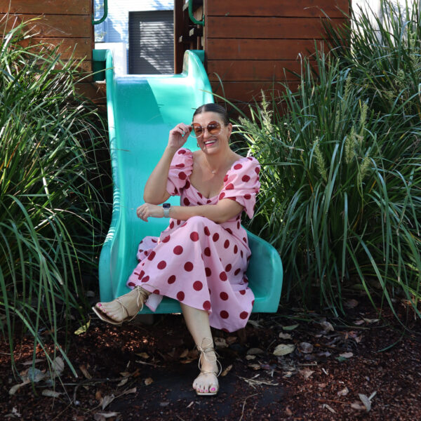 A woman wearing a pink and red dress on a slide in a playground