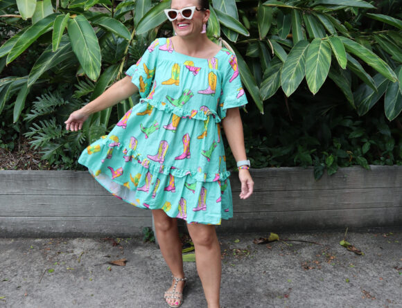 A woman wearing a mint coloured boot print dress and cowboy boots earrings