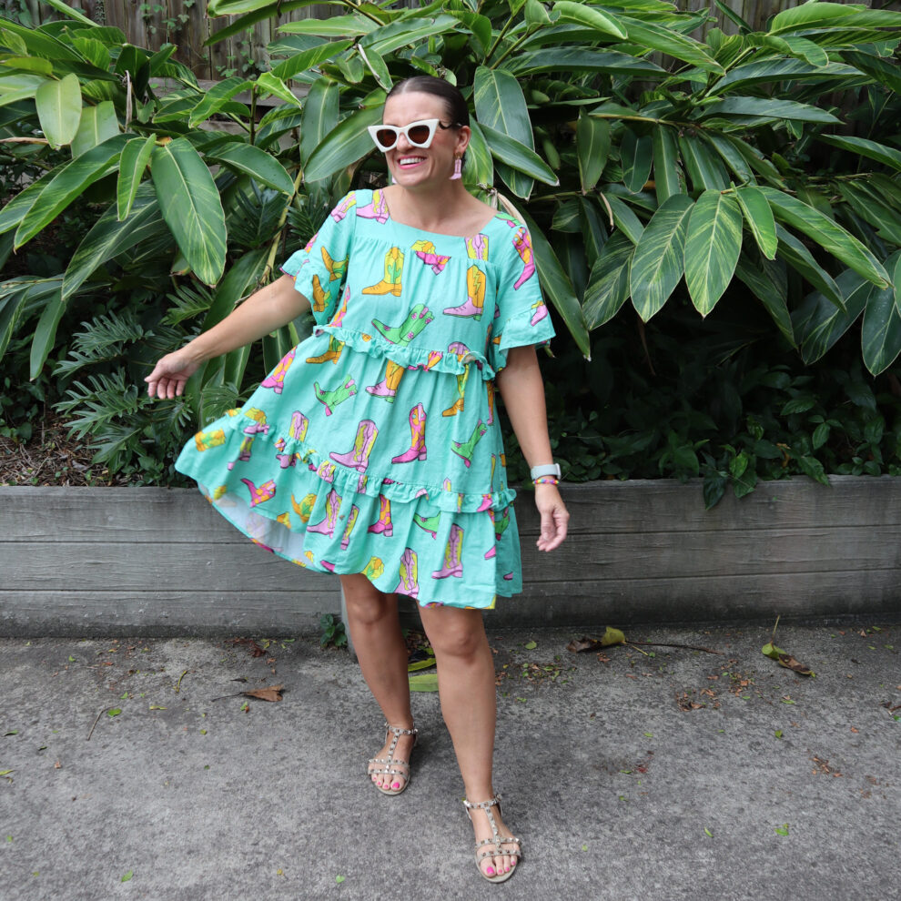 A woman wearing a mint coloured boot print dress and cowboy boots earrings